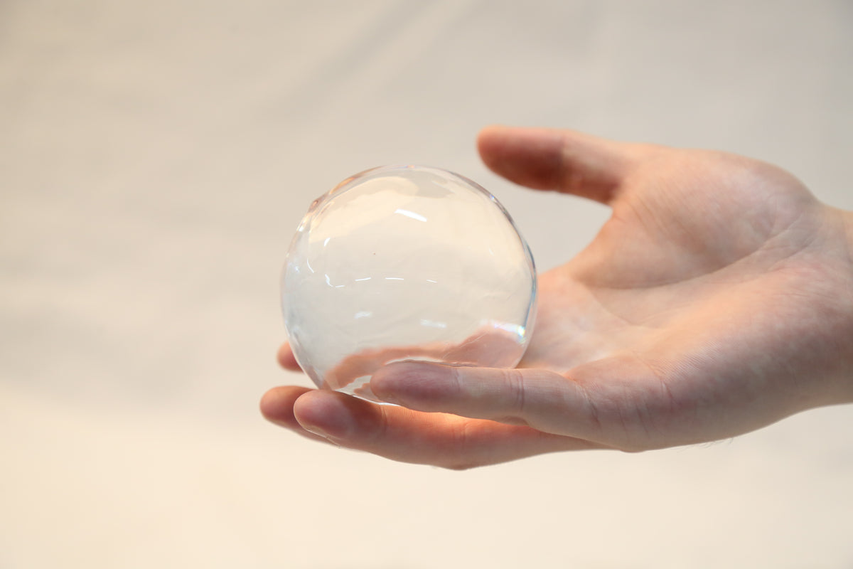 A hand holding a large clear ice ball