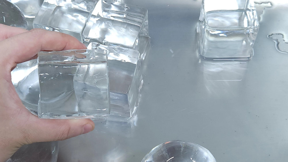 A picture of someone holding a large clear ice cube.